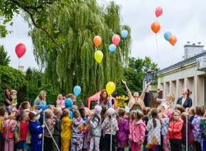 Grupa osób patrząca na odlatujące kolorowe balony.