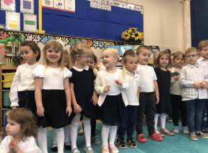 Małe dzieci (w eleganckich, galowych strojach) podczas występu z okazji Dnia Nauczyciela.